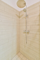 Shower faucets attached to tiled wall near glass partition and ornamental curtail in washroom at...