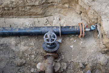 repair of urban underground communications and pipes. in a dug trench, the junction of two pipes and an iron branch to shut off the water supply