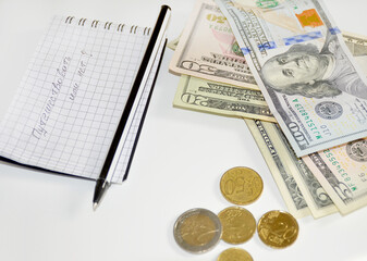 Obraz premium Notebook entry in Russian: to travel or not. counting money for summer holidays and a trip to the sea. notebook, pen, dollars and coins on a white background