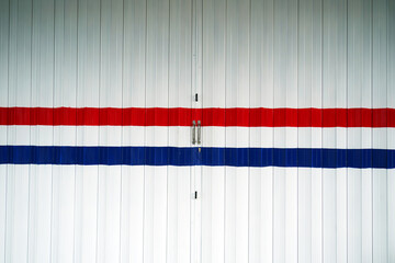 The red and blue line on the white door of the shop front