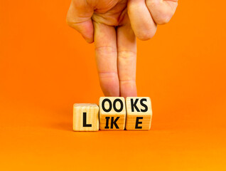 Looks like symbol. Concept words Looks like on wooden cubes. Businessman hand. Beautiful orange table orange background. Business, popular quotes and looks like concept. Copy space.