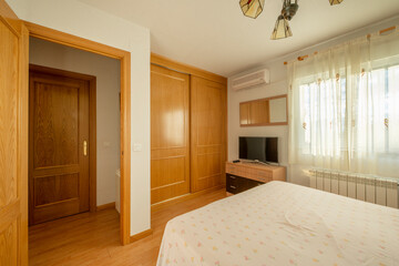 Bedroom with double bed, wardrobe with sliding oak doors, window with curtains, chest of drawers and flat screen TV