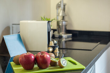 Corner of a kitchen with a black stone countertop with a white capsule coffee machine, designer...