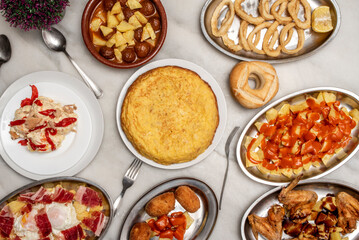 Set of delicious dishes and tapas of Spanish food, potato omelette, croquettes, patatas bravas, Russian salad, scrambled eggs with ham, Roman calamari, sausages to hell