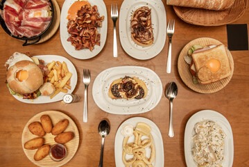 Plates and trays of typical recipes of Spanish gastronomy with croquette tapas, grilled ear, alioli potatoes, Andalusian-style squid, toast and broken eggs with ham