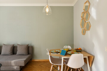 Living room with folding pine wood dining table and breakfast service with buns, fruit and juice