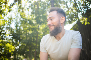 Naklejka na ściany i meble portrait of middle aged handsome bearded man dreaming in sunlight in summer park.