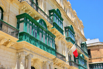 Traditional green balconies, Maltese architecture and national flag in Valletta, Malta