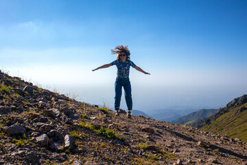 funny girl jump on the top of the mountain. panorama of the mountains