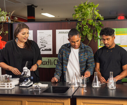 Two native students and a teacher performing an experiment