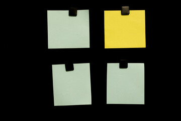Black noticeboard with three green sticky notes and one yellow note pinned