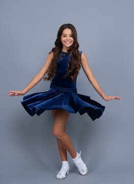 Teenager portrait with movement dress. Young teen child with flowing skirt. Teen girl fluttering dress in motion, isolated on gray. Positive and smiling emotions.