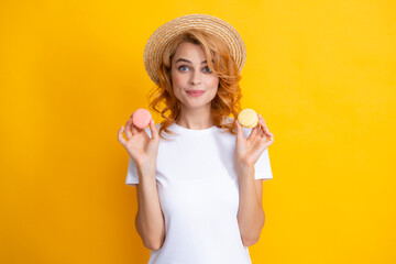 Young woman eating delicious macaroon on yellow background. Girl eat the macaron.