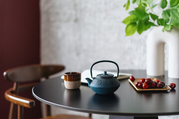 teapot with herbal tea and ceramic cup on wooden table