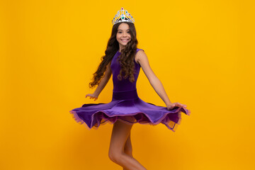 Movement windy dress. Teen child in queen crown isolated on yellow background. Princess girl in...