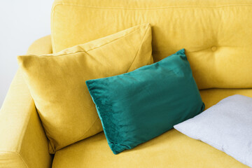 sofa with mustard velvet textile and pillows, closeup