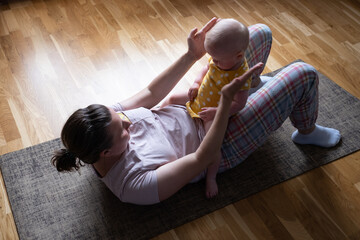 Caucasian mother with baby make yoga at home to be strong and healthy,