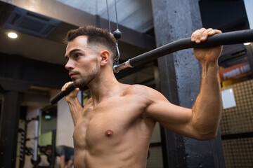 male model pulling up on horizontal bar in a gym