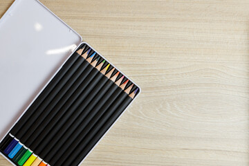 wooden colorful pencils in open steel box on wooden table