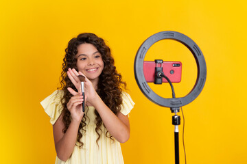 Teen girl speaking in front of camera for vlog isolated on yellow background. Teenager working as blogger, recording video blog. Happy teenager, positive and smiling emotions of teen girl.