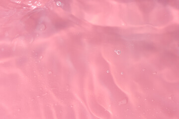 Obraz na płótnie Canvas Abstract background. The texture of the waves on a pink background. Bubbling water, splashes and drops.