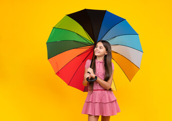 Summer dress. Happy teen girl holding rainbow umbella standing isolated on yellow background, isolated on white. Cheerful teenager child hold parasol.