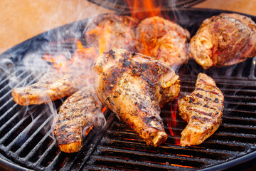 Traditional barbecue lamb shanks and saddle grilled as close-up on a charcoal grill with fire and smoke