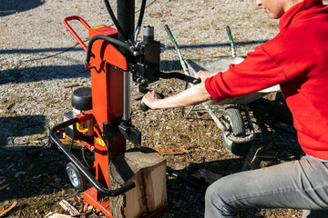 Close up of a Mid Adult Woman in Red Cloths Splitting Firewood with an Electric Splitter for Winter