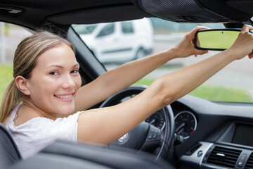 woman adjusting rear view mirror