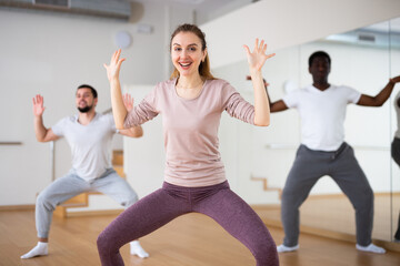 Young attractive woman visiting group choreography class, learning modern dynamic dances. Concept...