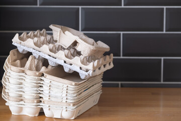 Fototapeta na wymiar a lot of egg carton boxes against black wall on the wooden countertop, recycling food packaging, reusable pack