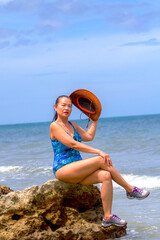 Woman with swimsuit sit on stone at beach