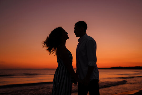 Silhouette of a couple of young lovers hugging on the beach duri