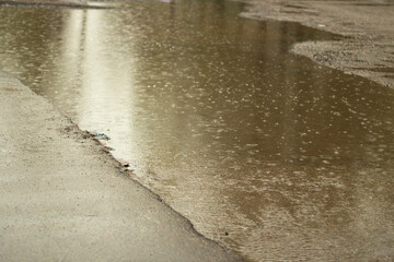 Rain outside. Large puddle in yard. Wet weather. Surface of puddle.