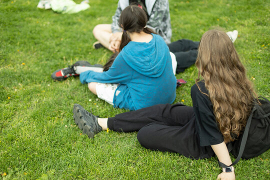 Children in summer relax on green grass. Girls in park.