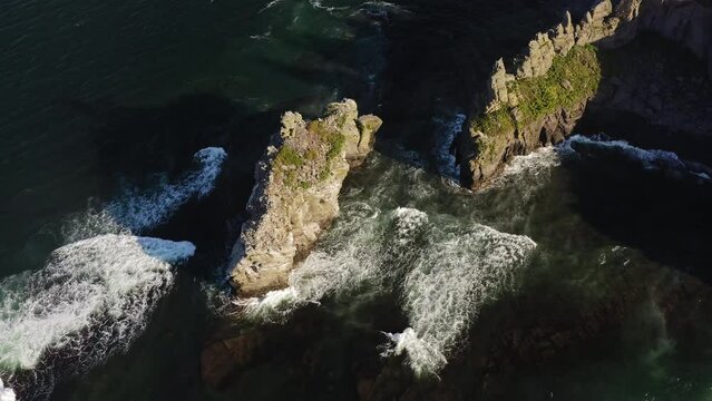 A bird's market on a rocky ledge in the shape of fingers on the seashore. Seagulls sit on the rocks. Waves crashing against the rocks at dawn. View from a drone.