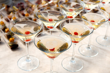 A row of glasses with champagne and cherries inside the glass are on the table.