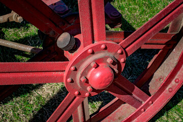 An old red wagon wheel on an antique tractor. The oil cap is covered in muck and dirt. Each wheel...