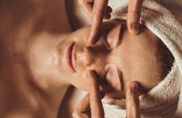 Top view of a Beautiful Caucasian woman receiving eye massage at spa salon. Facial beauty. Beauty...