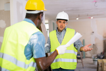 African-american foreman quarreling with his employee, caucasian man, about project documentation....