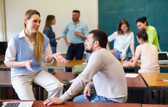 Man And Woman Students Having Small Talk In Classroom During Recess.