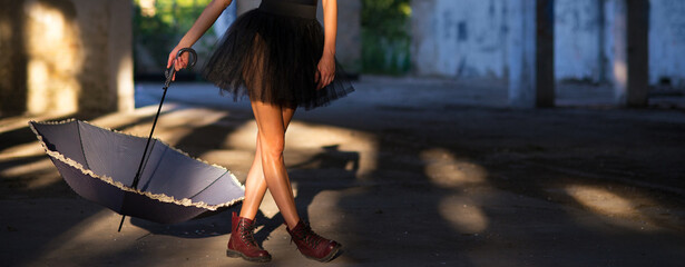 Goth ballerina holding umbrella posing in abandoned building