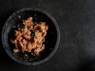 Grated coconut is mixed with spices consisting of garlic, chili, sugar, palm sugar, salt and lime leaves.