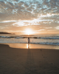 Sunrise on the beach with girl walking near the ocean