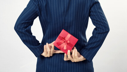 Business woman holding a gift box behind her back