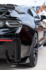 Obraz na płótnie Canvas Sport car at the start. Grille on the rear window of the car. Luxury black sports car fragment, rear aerodynamics carbon spoiler and rear lights.