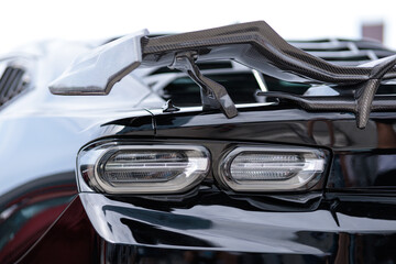 Luxury black sports car fragment, rear aerodynamics carbon spoiler and rear lights