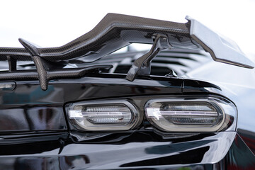 Luxury black sports car fragment, rear aerodynamics carbon spoiler and rear lights