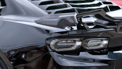 Obraz na płótnie Canvas Luxury black sports car fragment, rear aerodynamics carbon spoiler and rear lights