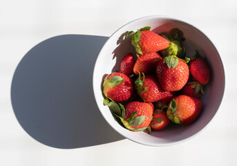 Top view of fresh strawberries in a white bowl isolated